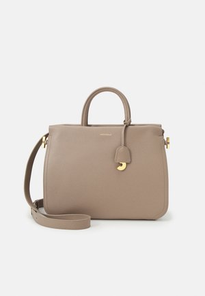 Sac à main en cuir taupe avec poignées supérieures, bandoulière amovible et détail en métal doré sur le devant sur fond blanc.