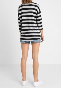 Czarny i szary pasiaste długie rękawy, noszone na postrzępionych szortach dżinsowych, w połączeniu z białymi trampkami. Prosty, luźny krój z zaokrąglonym dołem.