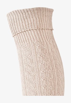 Calzino beige lavorato a maglia con polsino a coste, caratterizzato da un motivo testurizzato e un tessuto morbido e flessibile. Il design si estende fino a metà polpaccio.