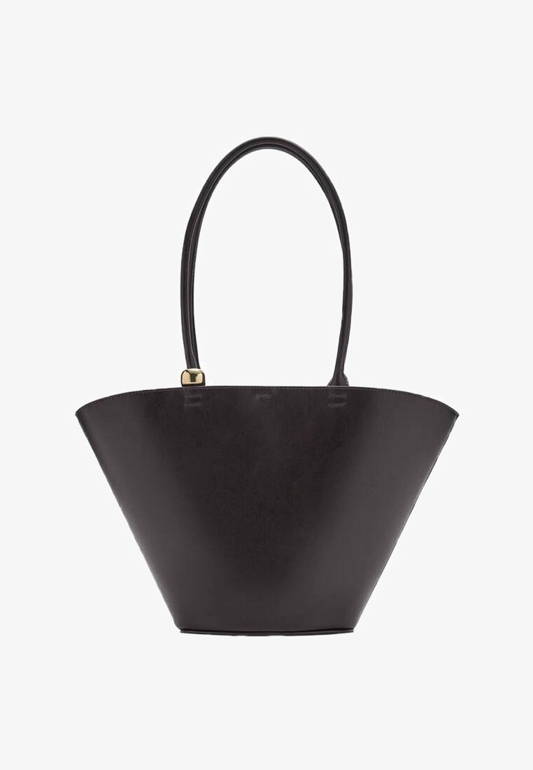 Sac à main noir en forme de trapèze avec une longue bandoulière unique et un petit accent doré près de la poignée sur fond blanc.