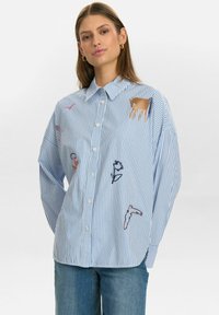 Gestreiftes, blaues Hemd mit Knopfleiste und Tierstickerei in Pink, Gold und Marineblau. Bietet eine lockere Passform und klassischen Kragen, aus leichtem Stoff hergestellt.