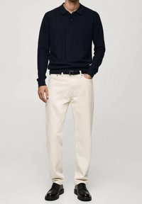 Marineblaues Langarm-Poloshirt, cremefarbene Hose und schwarze Schuhe. Das Kleidungsstück zeichnet sich durch eine lässige Passform und eine dezente Textur aus. Standardkragen-Design.