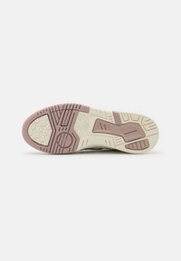 Suela de zapato con goma texturizada en crema y rosa claro. Presenta patrones geométricos y surcos para tracción y soporte.