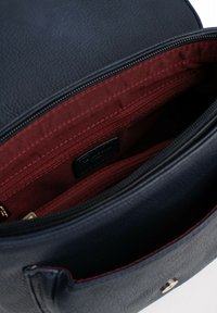 Borsa in pelle blu navy con interno in tessuto rosso, dotata di chiusura con zip e scomparti interni per l'organizzazione. Texture liscia e minima presenza di hardware.