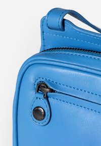 Borsa in pelle blu con finitura testurizzata, dotata di una cerniera nera e cuciture blu in contrasto. Include un attacco per la tracolla.