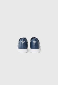 Navy blue leather sneakers with a white sole, featuring a logo on the back, round toe, and textured side panels.