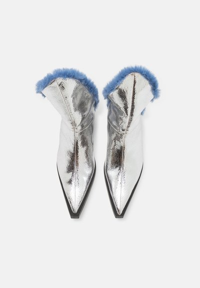 Silberne metallic Ankle Boots mit spitzem Zeh und schwarzem Fußbett, verziert mit einem blauen Kunstfellrand entlang der oberen Kante. Glatte Textur mit glänzender Oberfläche.