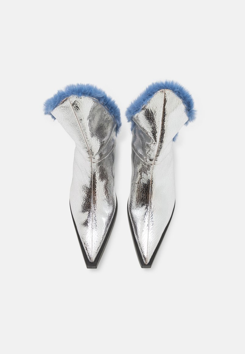 Silverfärgade metalliska ankelskoot med spetsig tå och svart sula, med en blå pälsbeklädnad längs övre kanten. Slät textur med en glänsande yta.