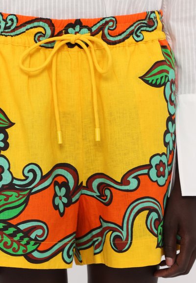 Yellow shorts with floral and swirl patterns in blue, orange, and green. Features an elastic waistband with a yellow drawstring.