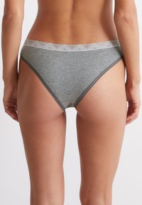 Grijze katoenen ondergoed met een decoratieve kanten tailleband. Het ontwerp heeft een klassieke snit en een zachte textuur, die eenvoudige lijnen benadrukt.