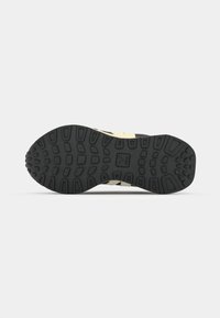 Black rubber shoe sole with a textured grip pattern, featuring tapered lugs and a cream-colored midsole detailing.