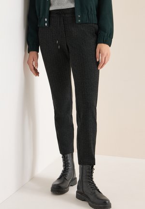 Svarta byxor med texturerat tyg och smal passform, med dragsko i midjan och sidofickor, tillsammans med svarta snörade stövlar.