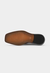Semelle d'une chaussure habillée en cuir marron avec un talon noir et une surface texturée, taille 41 indiquée sur la semelle.