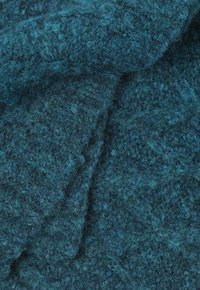 Tissu en laine texturé de couleur bleu canard profond avec une surface légèrement duveteuse, présentant des variations de teintes et une apparence riche et chaleureuse.