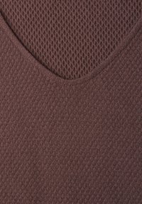 Gros plan d’un tissu marron avec un motif tricoté en forme de V présentant un tissage dense et texturé en haut et un tricot plus fin en dessous.