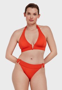 Rode halter bikini top met een diepe V-hals, gecombineerd met een low-rise bikini broekje met zijbandjes. Glad, rekbaar materiaal door heel het stuk.