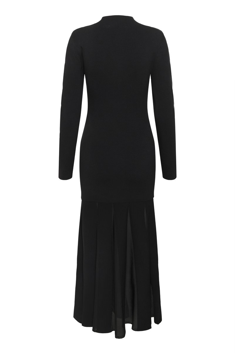 Schwarzes Kleid mit einem figurbetonten Strickoberteil und langen Ärmeln, das von der Taille bis zum Saum in einen schwingenden, gefältelten, transparenten Maxirock übergeht.