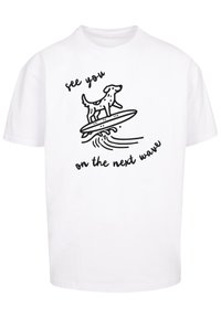 White cotton t-shirt featuring a black outline illustration of a dog on a surfboard with text "see you on the next wave."