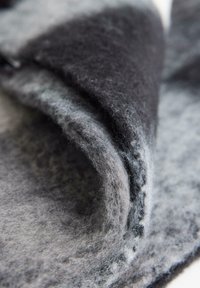 Tessuto in feltro di lana in diverse sfumature di grigio, con una superficie morbida e testurizzata che presenta sottili variazioni di colore e ombreggiatura.