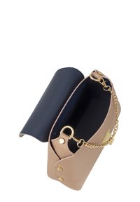 Borsa a mano in pelle beige con pattina blu navy, tracolla in catena dorata e chiusura a bottone. Interno foderato in tessuto scuro, che mette in risalto un design minimalista.