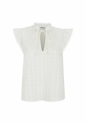 Blusa blanca con escote en forma de llave, mangas cortas en volantes y patrón de bordado de ojo de perdiz. Detallada con un borde ondulado.