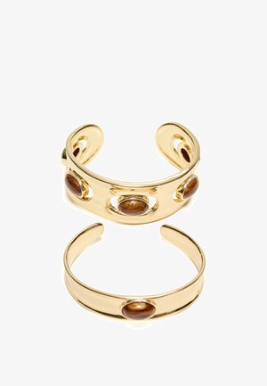 Deux bracelets manchette ouverts en or, chacun avec des pierres ovales marron lisses, l'un plus large avec trois pierres et l'autre plus étroit avec une pierre.