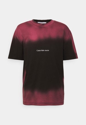 Lyhythihainen t-paita tumman burgundinpunaisena, jossa liukuvärjäys mustaan. Pyöreä pääntie ja valkoinen "Calvin Klein Jeans" -logo rinnassa.