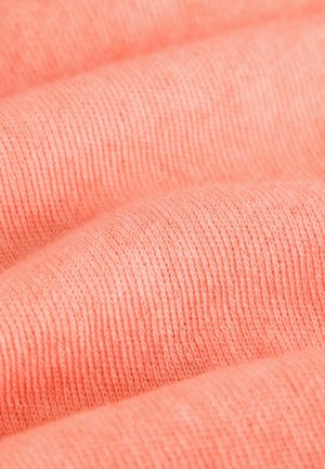 Korallipink värviga kangas, mille pehme sooniline tekstuur näitab õrnu paksuse ja värvi sügavuse variatsioone voldikutes.