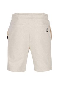 Shorts de sport beiges avec taille à cordon, deux poches arrière et un petit logo sur le côté gauche. Texture douce et design décontracté.