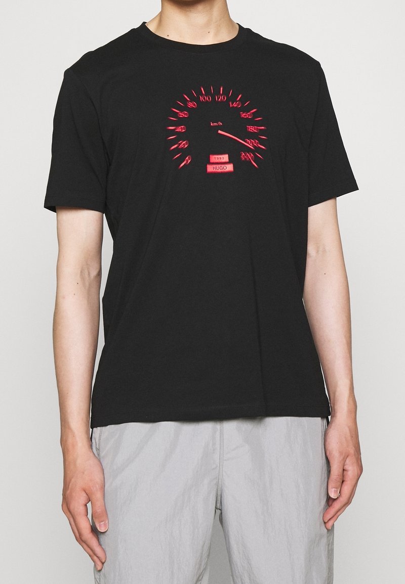 T-shirt en coton noir avec un graphique de compteur de vitesse rouge sur le devant, manches courtes et col rond.