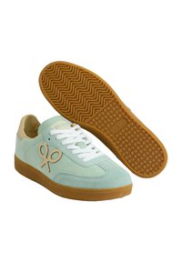 Zapatillas de ante verde menta con cordones blancos, suela de goma y acentos beige. El logo presenta un diseño de tijeras en el lateral.