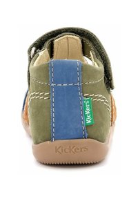 Zapato infantil de ante en verde, azul y marrón con una cinta de Velcro. Presenta una suela de goma y el logo "Kickers" en la parte trasera.