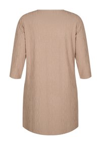 Beige tunika med en texturerad mönster, med trekvartsärmar och rund halsringning, tillverkad av ett mjukt, lätt material.