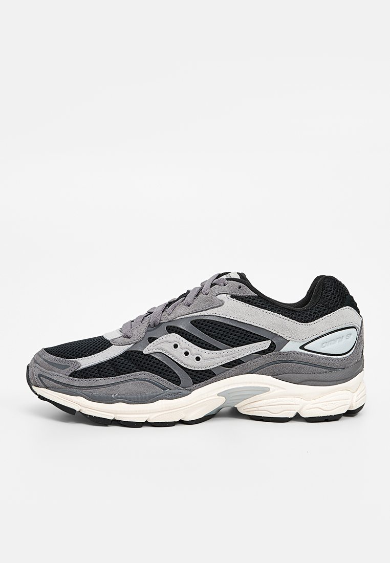 Chaussure de course grise et noire avec tige en mesh, empiècements en daim, fermeture à lacets et semelle intermédiaire blanche rembourrée sur un fond uni.