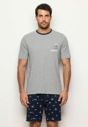 T-shirt di cotone grigia con maniche corte, colletto a costine blu navy e grafica a tema vela sul lato sinistro del petto. Abbinato a pantaloni corti blu navy con stampe nautiche bianche.
