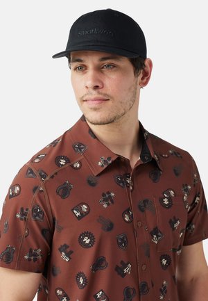 Brown short-sleeve shirt with graphic patterns, featuring various illustrations; paired with a black cap displaying "Smartwool" logo.