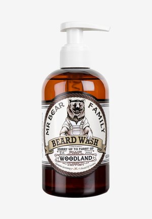 Bouteille en verre ambré avec un distributeur à pompe blanc. L'étiquette présente une illustration d'ours, du texte en noir et or, ainsi que des bordures décoratives.