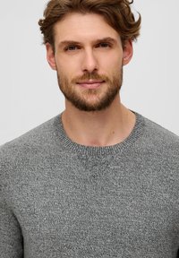Grauer Strickpullover mit Rundhalsauschnitt, der ein strukturiertes Muster und gerippte Bündchen aufweist. Das Material wirkt weich und gemütlich.