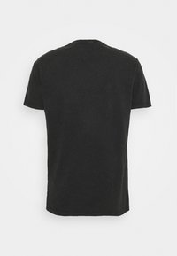 Camiseta de algodón negra, de manga corta, con cuello redondo y corte relajado. Presenta una textura ligeramente desgastada que proporciona un aspecto vintage. Sin gráficos ni acentos.