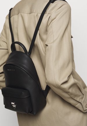 Schwarzer Leder-Rucksack mit abgerundeter Form, verstellbaren Riemen und einer Fronttasche. Mit silbernem Totenkopf-Akzent auf der Tasche.