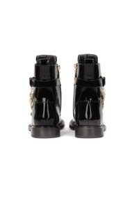 Botines de charol negro con un diseño elegante, acentos de hardware dorado y un detalle de correa lateral. Suela plana con tacón.