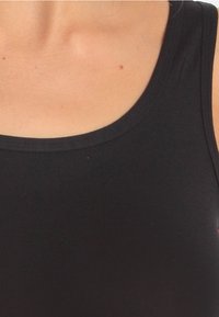 Zwarte tanktop met een zachte textuur, een ronde halslijn en naadloze bandjes, ontworpen voor comfort en bewegingsvrijheid.