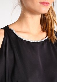 Black satin blouse featuring a wide neckline adorned with a silver rhinestone trim, soft texture, and short sleeves.