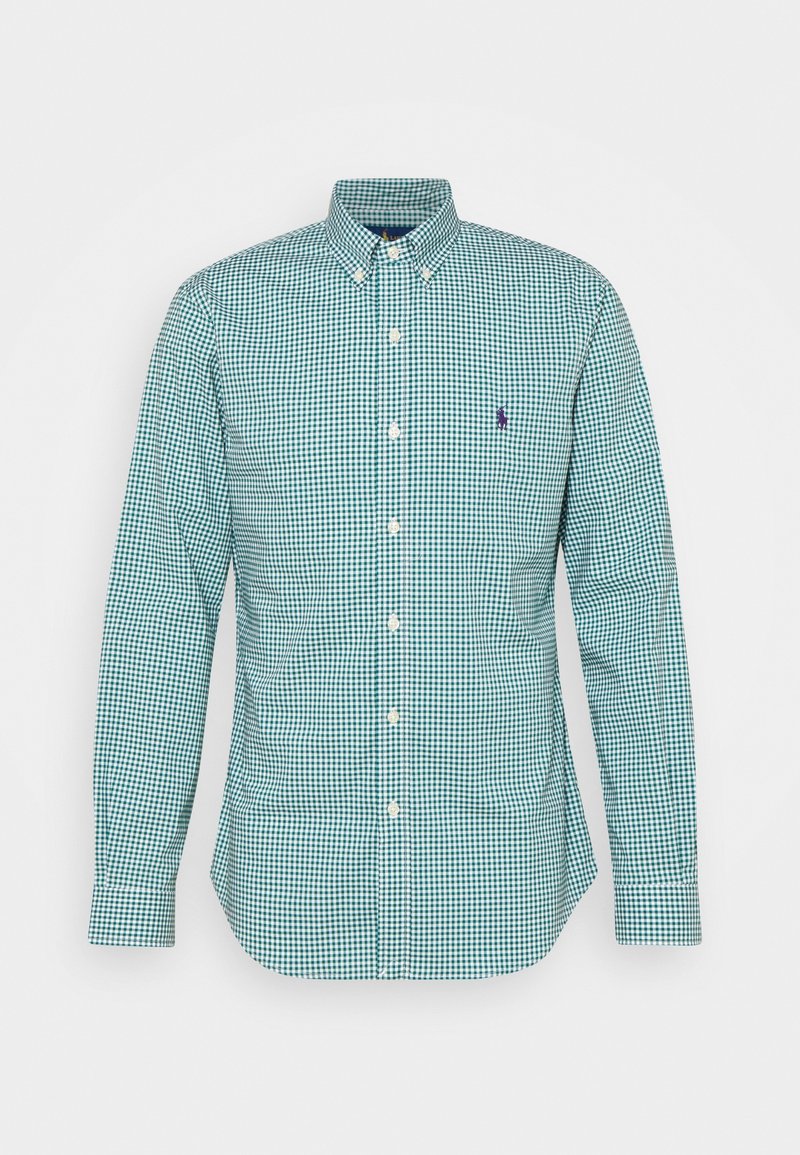 Grön och vit rutig långärmad skjorta med knappar och krage, som har ett litet lila emblem på bröstet.