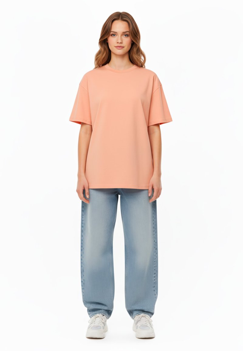 T-shirt oversize pesco con maniche corte, abbinato a jeans baggy blu chiaro e sneakers bianche. Tessuto morbido, design semplice, senza motivi.
