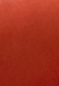 Texture de tissu rouge uni avec un motif tissé subtil et de légères variations d'ombrage sur la surface.