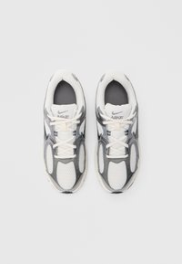 Αθλητικά παπούτσια Nike με επάνω μέρος από δίχτυ σε λευκό και γκρι, σχεδιασμό με κορδόνια, επενδεδυμένη γλώσσα και διακοσμητικά πάνελ στα πλευρά με υφή. Λαστιχένια σόλα.