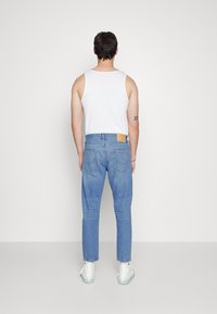 Uns jeans azuis claros em denim, com um corte reto, um patch de marca em pele na parte de trás e um ajuste casual.