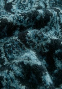 Kötött anyag teal és tengerészkék árnyalatokban, foltos textúrával; puha és bolyhos, diszkrét absztrakt mintával átszőve.