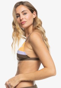 Bruine driehoek bikini top met oranje, lavendel en crèmekleurige blokken. Dunne schouderbandjes, gladde stof, kleine logo-detail aan de voorkant.
